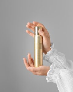 Female hands holding a bottle of nail polish on a gray background