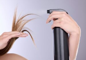 Hair care, beauty and hands with spray in studio isolated on a gray background. Cosmetics product,