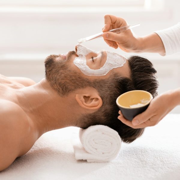 Bearded man getting face treatment at spa salon